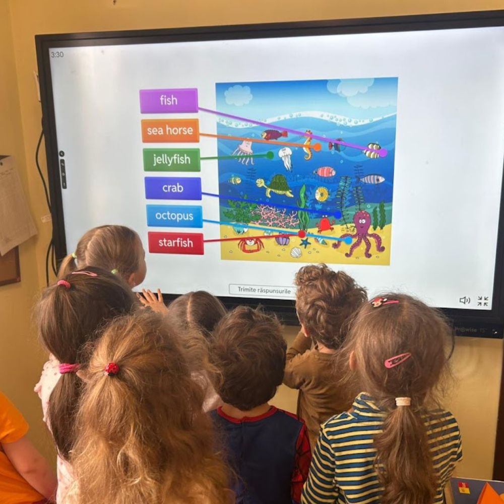 Copii folosind tabla interactivă la Academia Viitorilor Exploratori